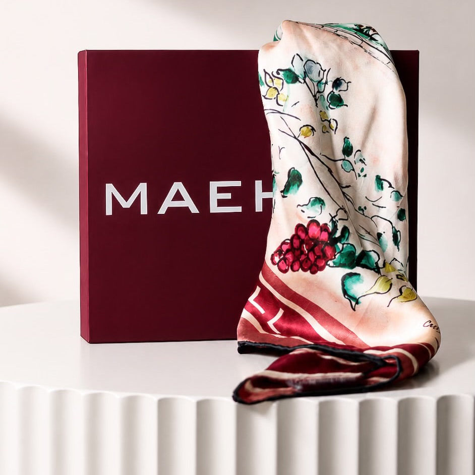 MAEHILL Tully square scarf in 100% Mulberry silk featuring a colorful watercolor print draped over a branded box.