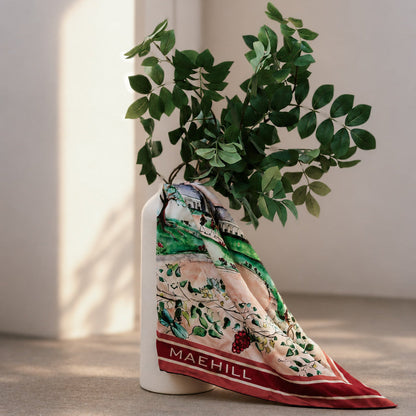 MAEHILL Tully square scarf in 100% Mulberry silk featuring a vibrant watercolor landscape print draped on a vase.
